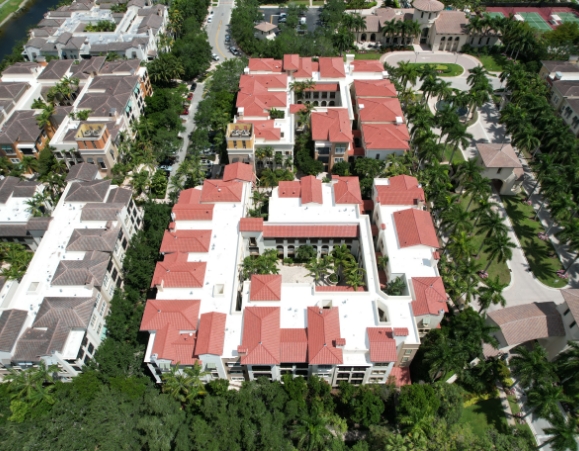 High-altitude aerial view of a multi-family condominium complex with red tile roofs and white flat roof sections.