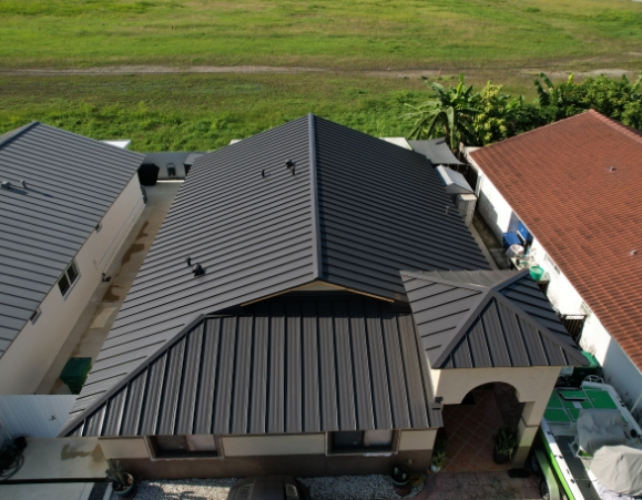 Aerial view of a residential home featuring a newly installed dark black standing seam metal roof.