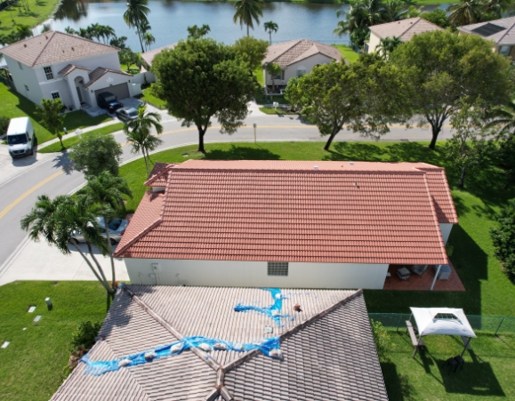 Aerial view of a suburban house featuring a terracotta concrete tile roof near a lake.