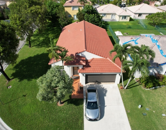 Aerial view of a suburban Florida home with a newly installed terracotta tile roof and concrete driveway.