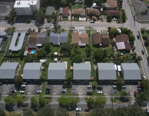 Overhead aerial view of a suburban neighborhood displaying row houses with light gray metal roofs.