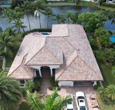 Aerial view of a luxury waterfront residence with a newly installed tan flat concrete tile roof.